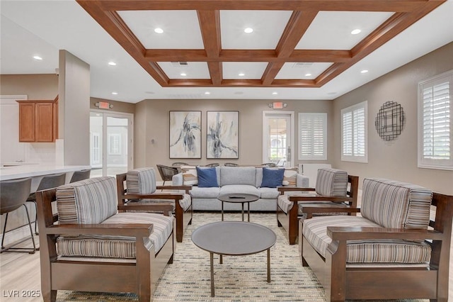 living room featuring coffered ceiling, light hardwood / wood-style floors, a wealth of natural light, and beamed ceiling