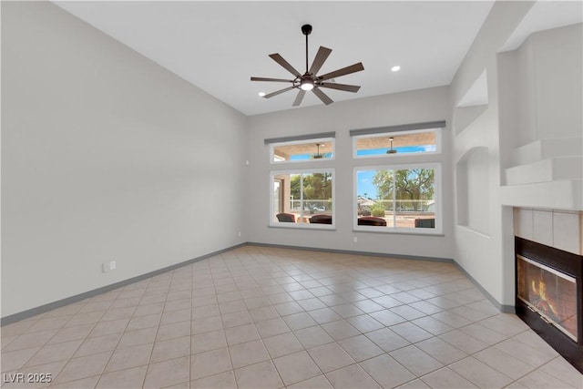 unfurnished living room with a fireplace, ceiling fan, and light tile patterned floors