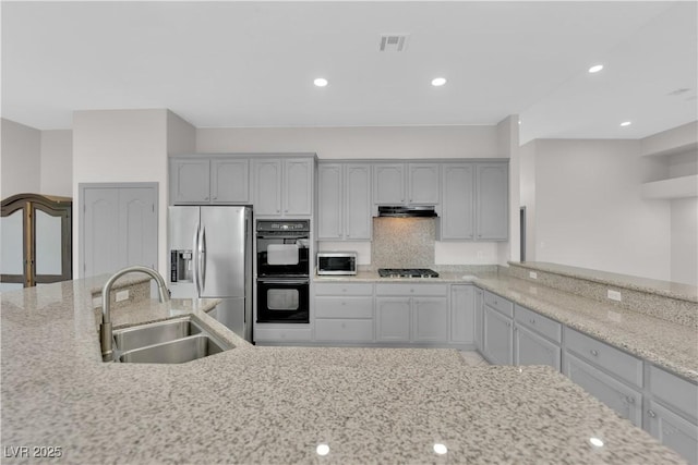 kitchen featuring gas stovetop, gray cabinets, double oven, stainless steel fridge, and sink