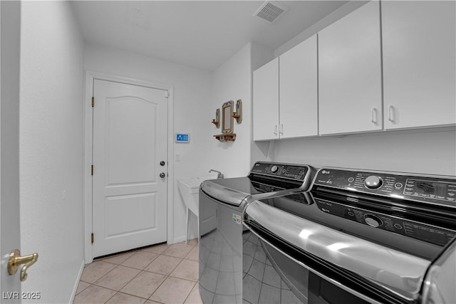 washroom with washer and dryer, light tile patterned floors, and cabinets