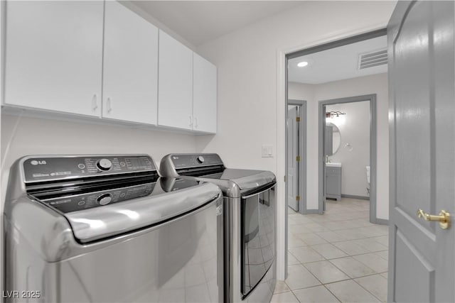 laundry room with cabinets, light tile patterned flooring, and independent washer and dryer