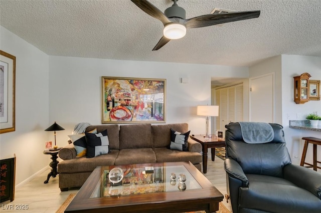 living room featuring a textured ceiling, ceiling fan, and light hardwood / wood-style floors