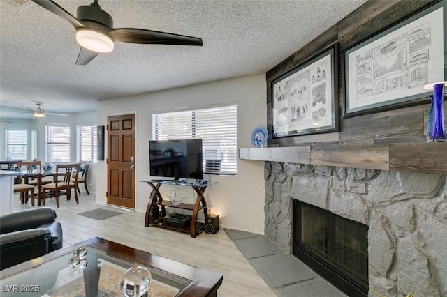 living room with a textured ceiling, a stone fireplace, and a wealth of natural light