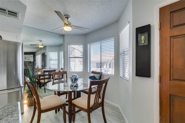 dining area featuring ceiling fan, light hardwood / wood-style floors, and a textured ceiling