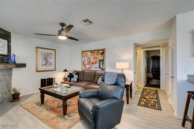 living room with a textured ceiling, ceiling fan, and light hardwood / wood-style flooring