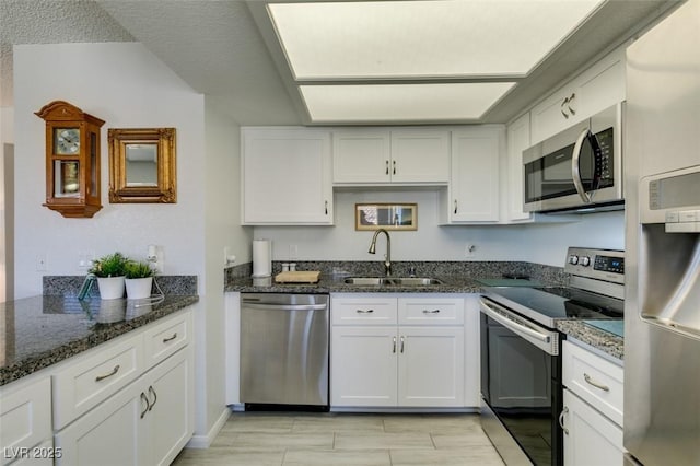 kitchen with sink, white cabinets, dark stone countertops, and appliances with stainless steel finishes