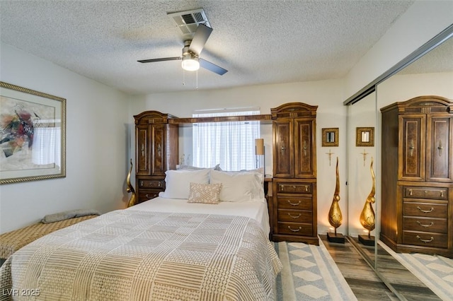 bedroom with hardwood / wood-style floors, a closet, ceiling fan, and a textured ceiling