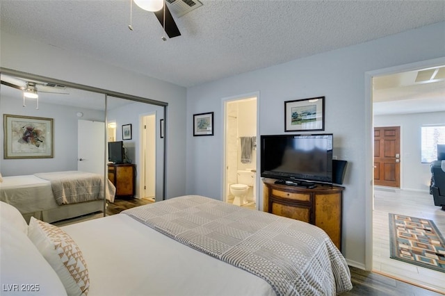 bedroom featuring a textured ceiling, ceiling fan, a closet, dark hardwood / wood-style floors, and ensuite bath