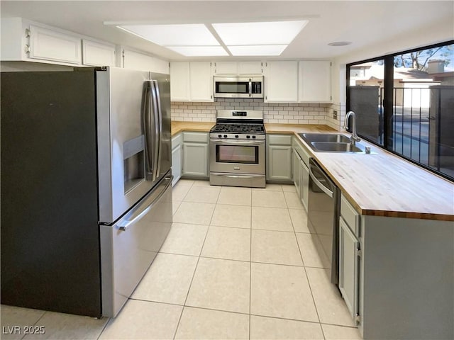 kitchen featuring light tile patterned floors, gray cabinets, appliances with stainless steel finishes, tasteful backsplash, and sink