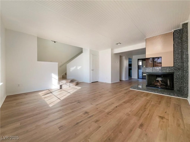 unfurnished living room with a tile fireplace and hardwood / wood-style floors