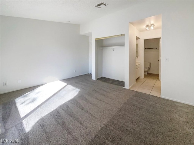 unfurnished bedroom featuring light carpet, a closet, and connected bathroom