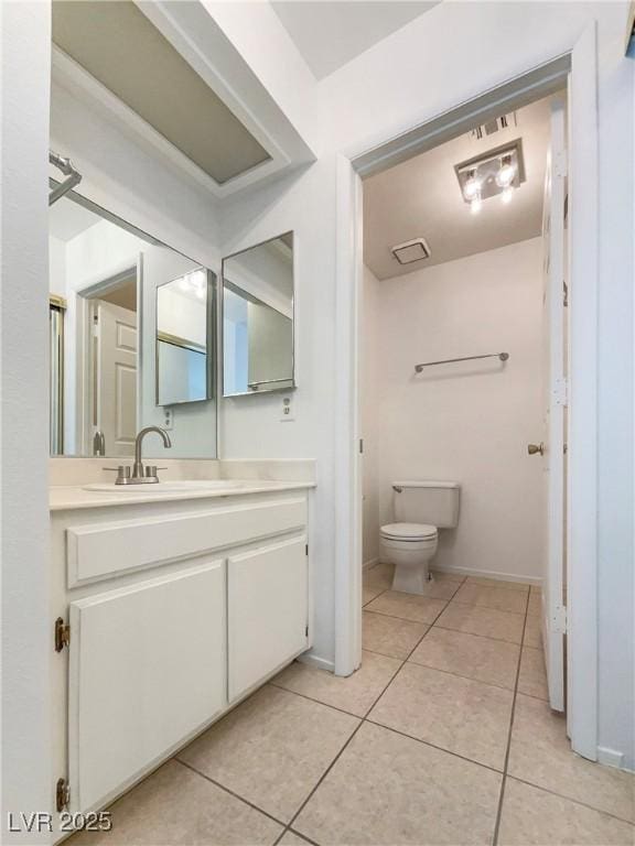 bathroom with toilet, vanity, and tile patterned flooring