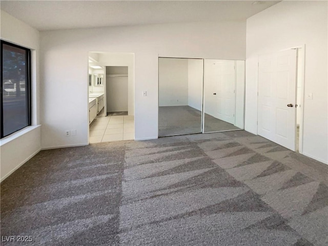 unfurnished bedroom featuring light colored carpet and ensuite bath