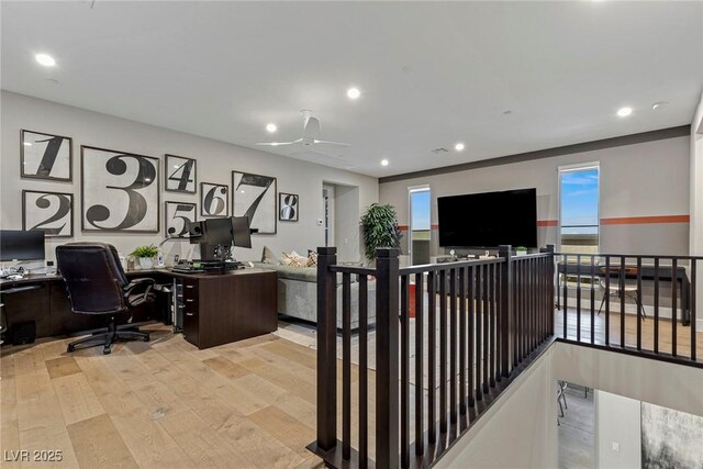 office featuring light hardwood / wood-style floors, ceiling fan, and a healthy amount of sunlight