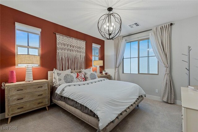 carpeted bedroom featuring multiple windows and a notable chandelier