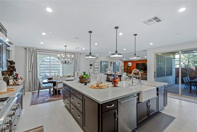 kitchen featuring sink, stainless steel appliances, an island with sink, dark brown cabinetry, and pendant lighting