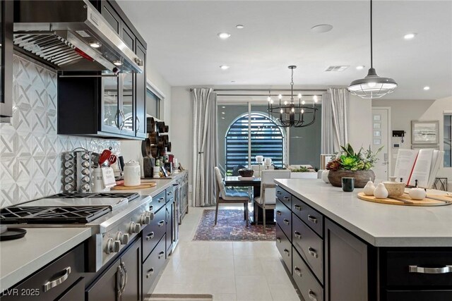 kitchen featuring tasteful backsplash, stainless steel gas stovetop, hanging light fixtures, extractor fan, and a chandelier