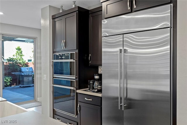 kitchen with stainless steel built in refrigerator, black double oven, and dark brown cabinets