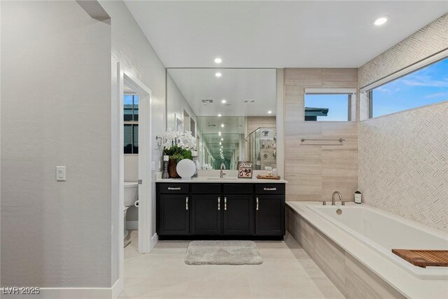 full bathroom with toilet, tile walls, independent shower and bath, and vanity