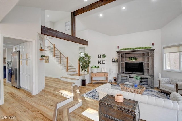 living room featuring a towering ceiling, light hardwood / wood-style floors, and beamed ceiling