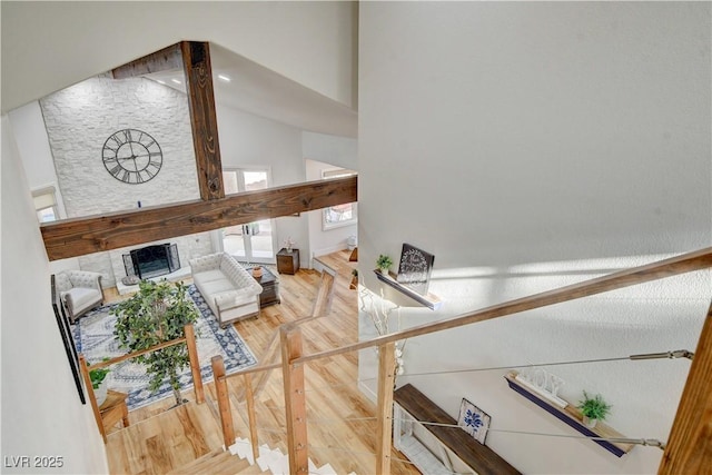 interior space with a high ceiling, a stone fireplace, and hardwood / wood-style floors