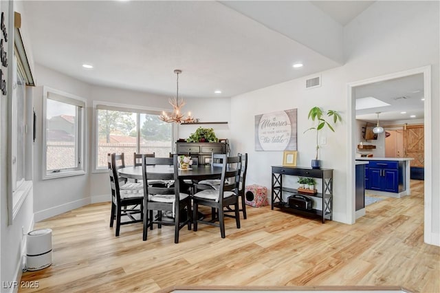 dining area featuring an inviting chandelier, a barn door, and light hardwood / wood-style flooring