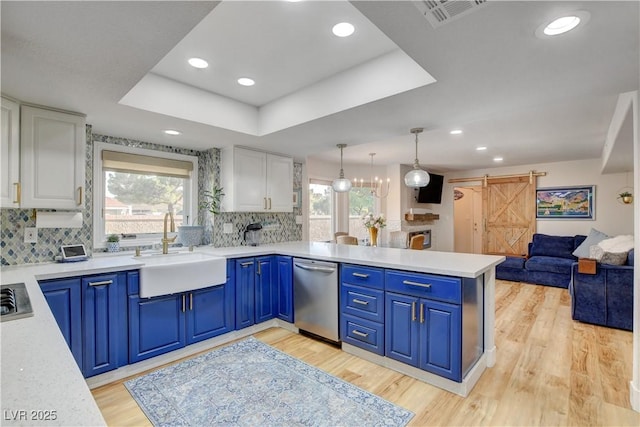 kitchen featuring sink, white cabinets, stainless steel dishwasher, blue cabinetry, and a barn door