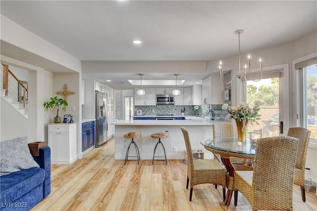 kitchen with hanging light fixtures, decorative backsplash, blue cabinetry, white cabinets, and appliances with stainless steel finishes