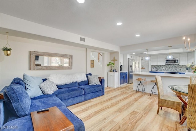 living room featuring a chandelier and light wood-type flooring