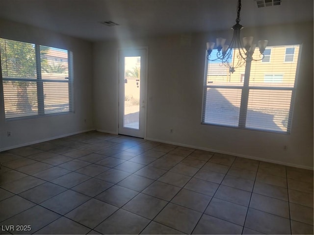 unfurnished room with a notable chandelier, tile patterned flooring, and a wealth of natural light