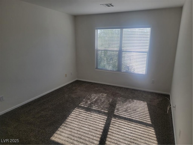 spare room with dark colored carpet