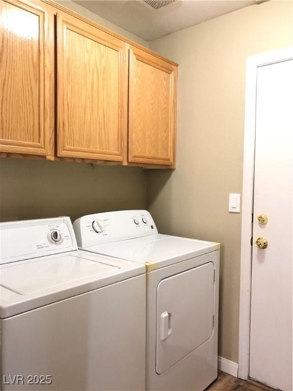 clothes washing area with washer and dryer, wood-type flooring, and cabinets