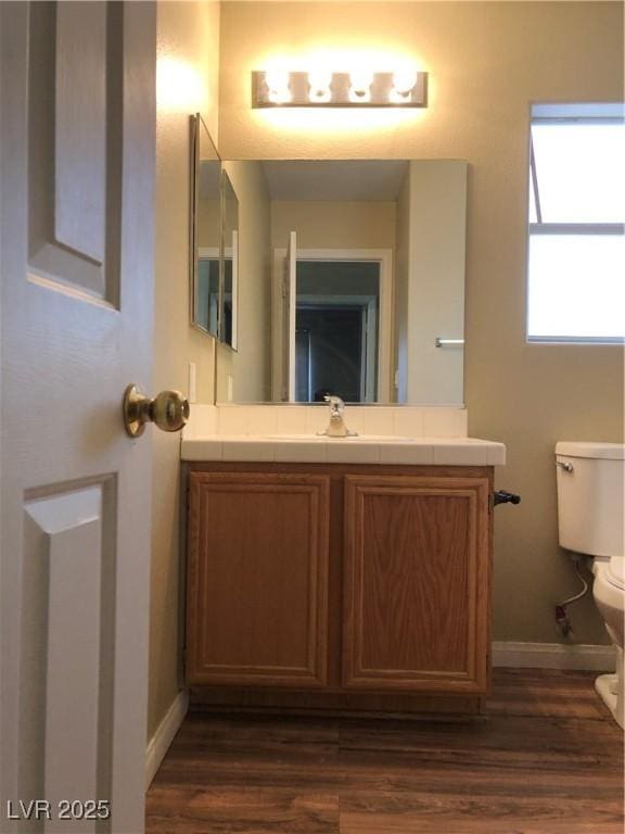 bathroom with toilet, vanity, and hardwood / wood-style flooring