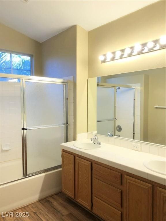 bathroom with combined bath / shower with glass door, hardwood / wood-style floors, vaulted ceiling, and vanity