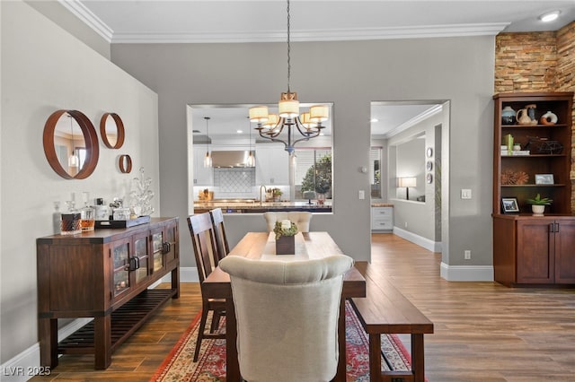 dining space with hardwood / wood-style flooring, an inviting chandelier, crown molding, and sink