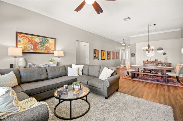 living room featuring ceiling fan with notable chandelier, crown molding, and wood-type flooring