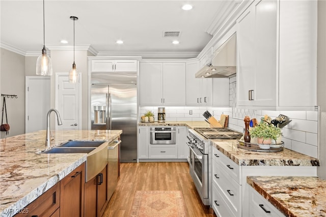 kitchen with premium appliances, hanging light fixtures, and white cabinetry