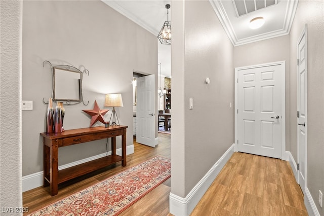 corridor featuring a notable chandelier, ornamental molding, and wood-type flooring