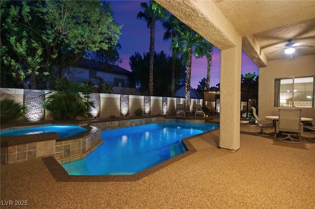 pool at dusk featuring a patio area, ceiling fan, and an in ground hot tub