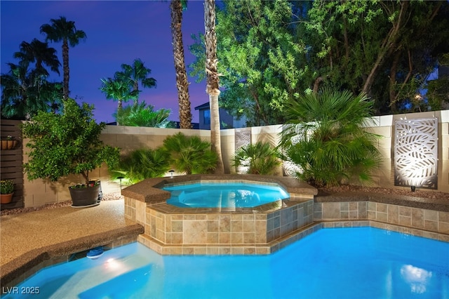 pool at dusk with an in ground hot tub