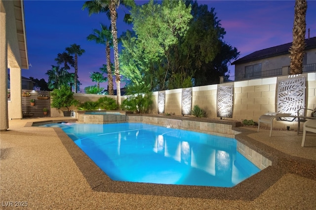 pool at dusk featuring an in ground hot tub