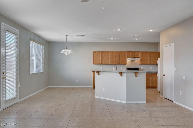 kitchen featuring a kitchen island with sink, pendant lighting, white refrigerator, and light tile patterned floors