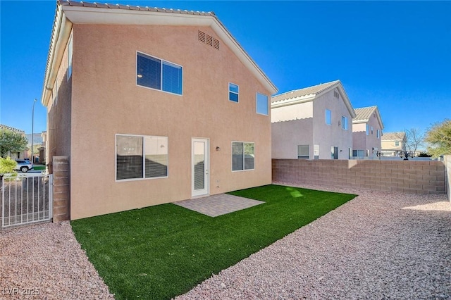 back of house with a patio and a lawn