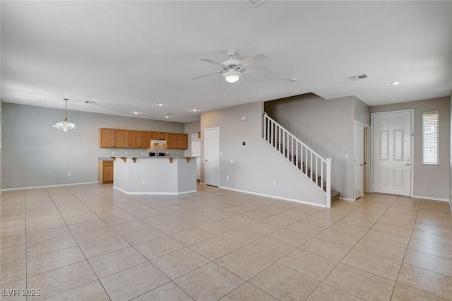 unfurnished living room featuring ceiling fan with notable chandelier and light tile patterned floors