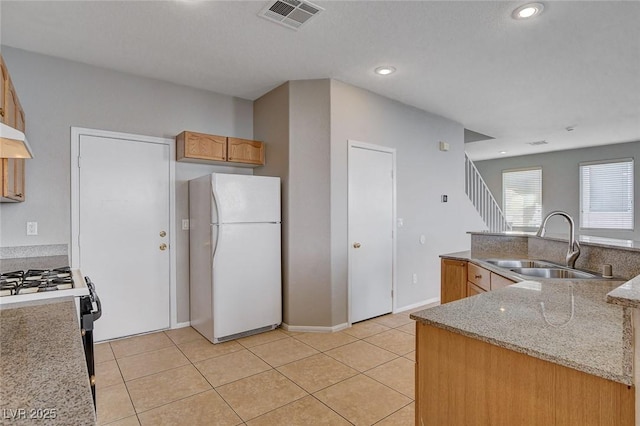 kitchen with black gas range, light stone countertops, light tile patterned floors, white refrigerator, and sink