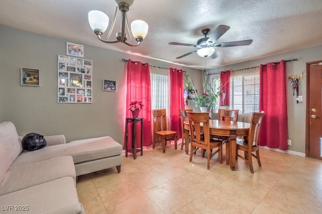 dining area featuring ceiling fan with notable chandelier and a textured ceiling