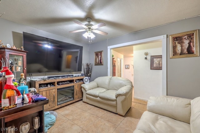 living room with a textured ceiling, ceiling fan, and light tile patterned floors