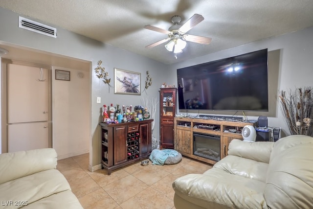 living room featuring a textured ceiling, ceiling fan, and light tile patterned floors