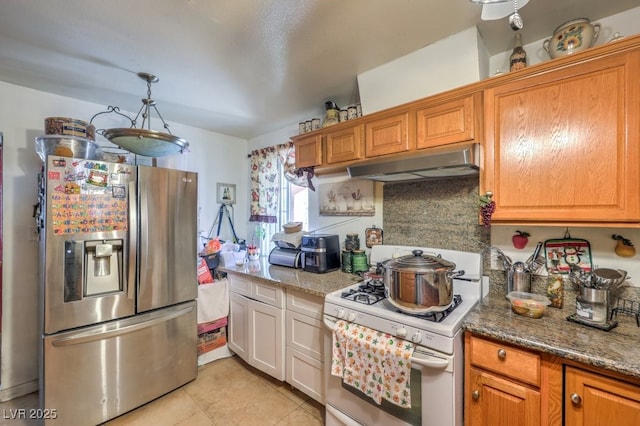 kitchen with white range with gas cooktop, dark stone counters, backsplash, and stainless steel refrigerator with ice dispenser