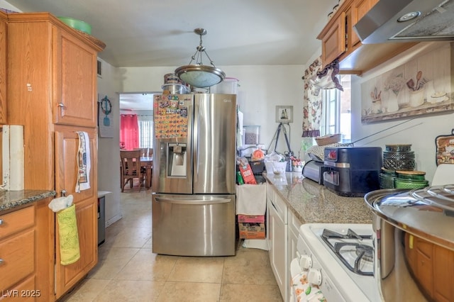 kitchen with light tile patterned floors, a wealth of natural light, light stone counters, and stainless steel fridge